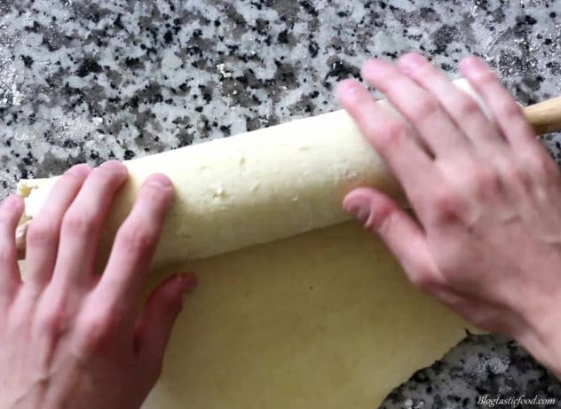 Rolled pastry being rolled up on a rolling pin.