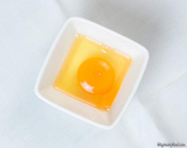 A photo of a cracked egg in a ramekin.
