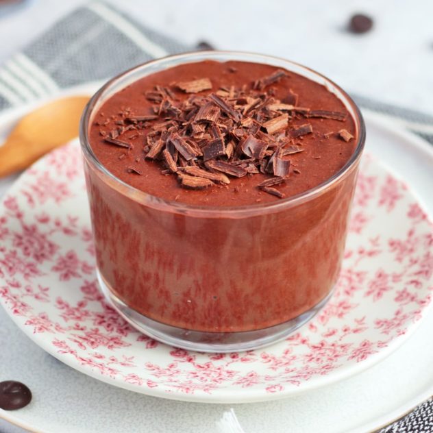 A vegan chocolate mousse served in a small glass dish, garnished with chocolate shavings.