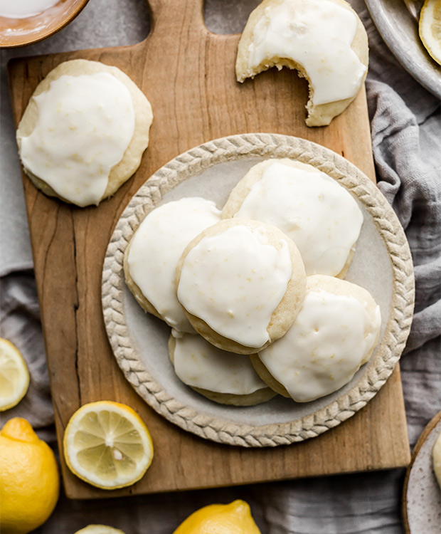 4 lemon ricotta cookies on a plate, with more cookies around them. 