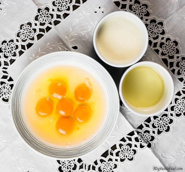 An overhead photo of eggs, vegetable oil and almond milk in seperate bowls and/or ramekins.