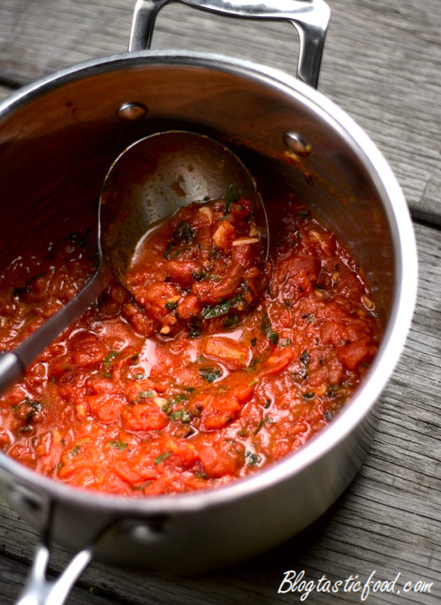 A pot of fresh tomato sauce with a ladle in it.