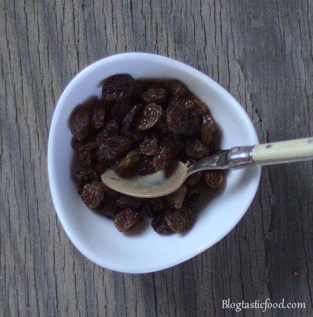 Sultanas and a small spoon in a mini bowl.