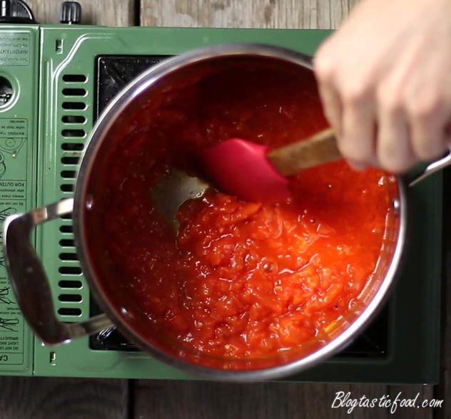 Tomato sauce being stirred in a pot.