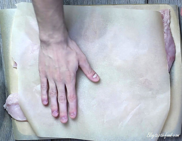 A sheet of baking paper over chicken breasts.