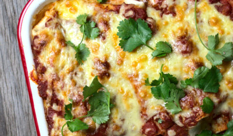 An overhead shot of cheesy enchiladas in a tray.