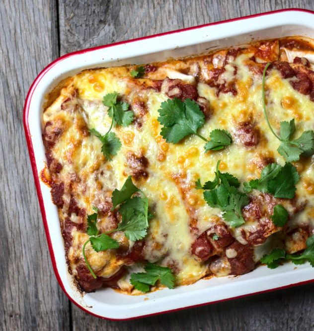 An overhead shot of cheesy enchiladas in a tray. 