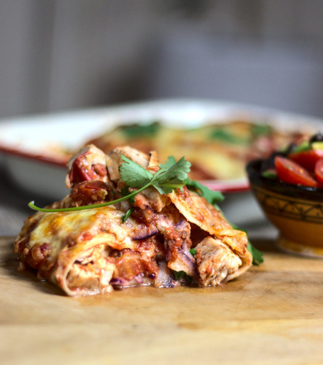 an eye level shot of a halved enchilada, showing all of the ingredients inside.